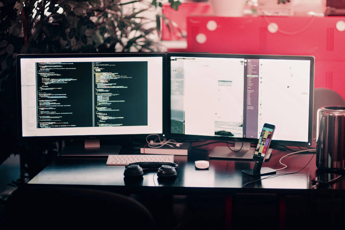 Zwei Monitore an einem Arbeitsplatz – links Programmcode, rechts die fertige Website im Browser