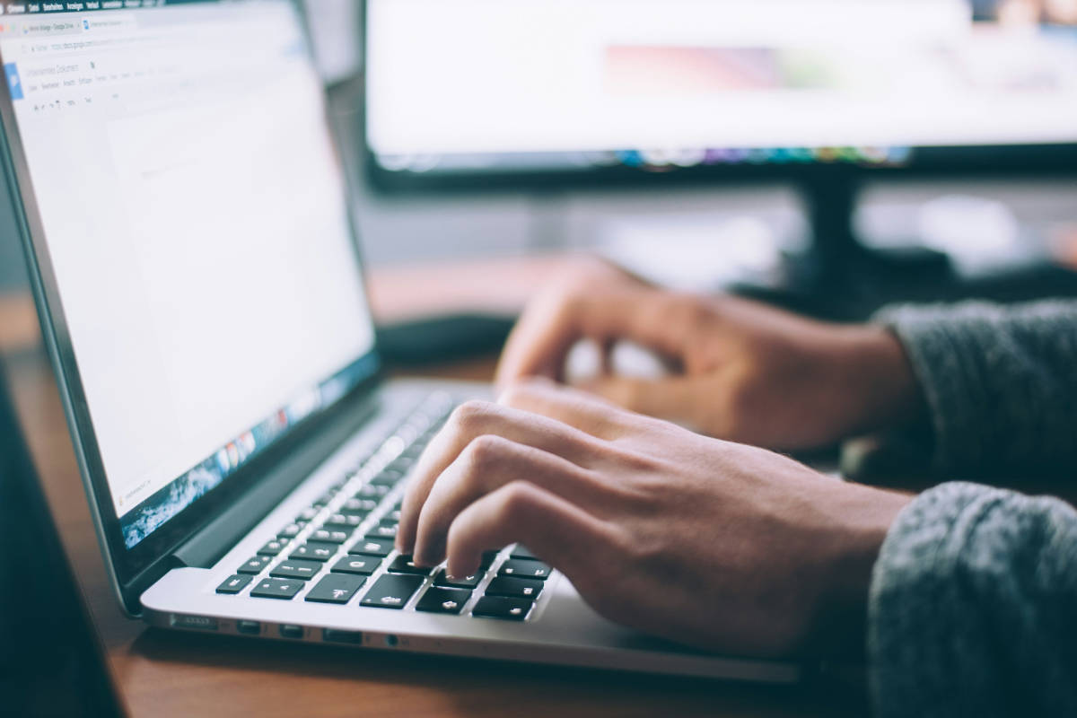 Hände tippen an einem Laptop in einem Textdokument – Inhalte für die neue Website vorbereiten