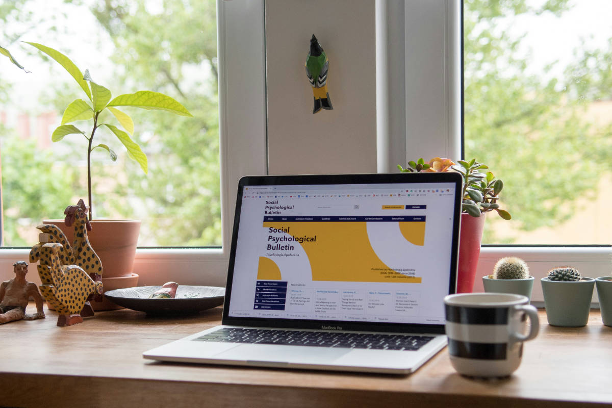 Laptop mit geöffneter Website auf einem Schreibtisch am Fenster – Websites als Quelle für KI-Suchsysteme